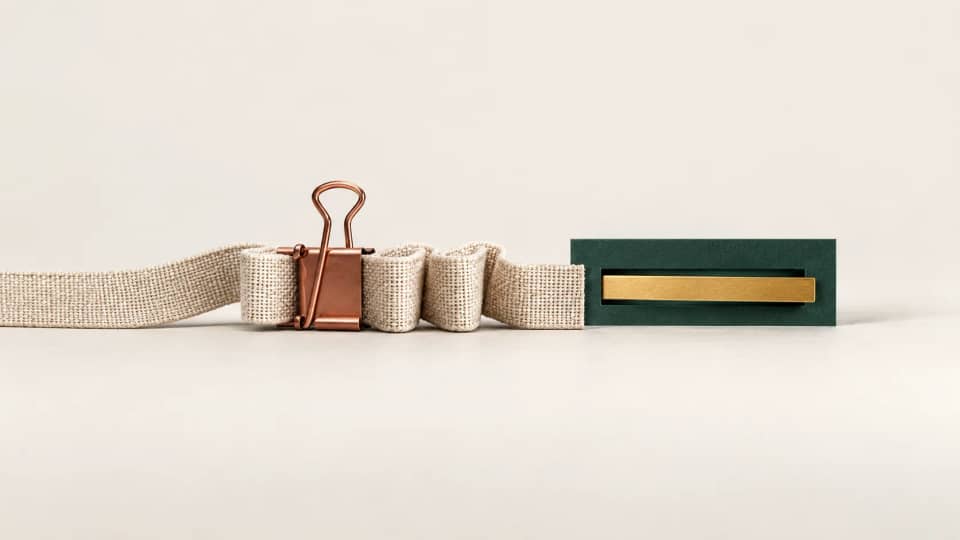 An intact linen strip held by a copper pause clip stops short of a green receiving slot crossed by a gold bar.