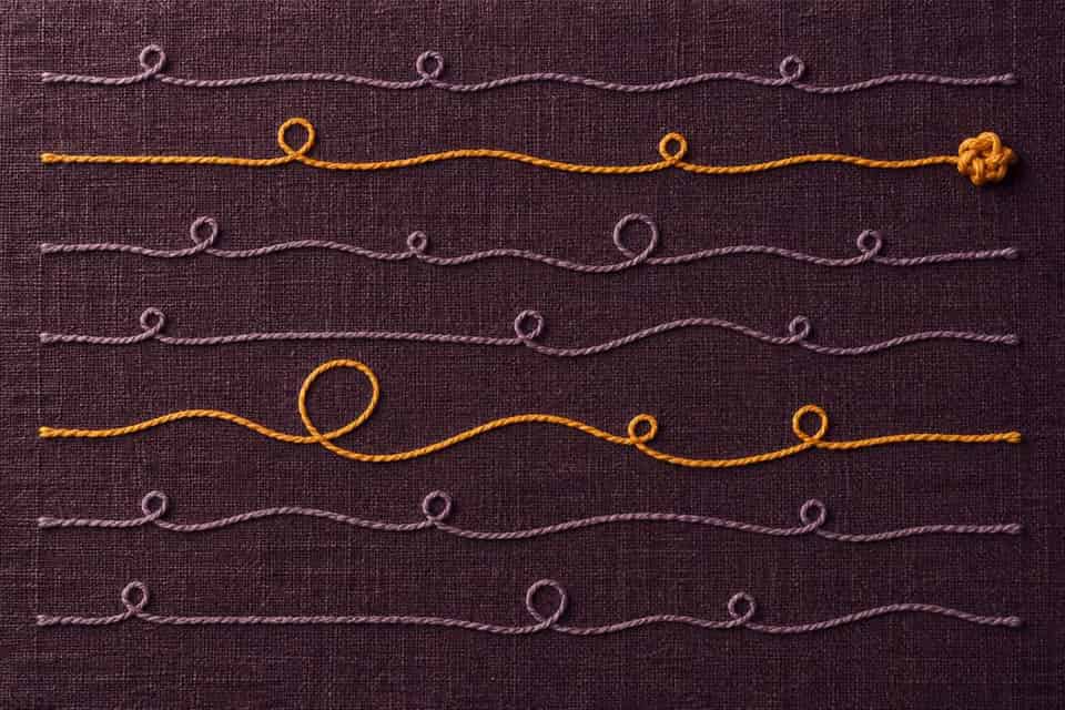 Two saffron thread paths stand out among lavender paths on plum fabric, each preserved from beginning to end.
