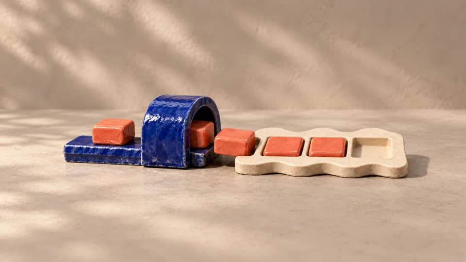 Coral tiles pass through a blue arch into a partly assembled ivory shape whose final recess is still empty.