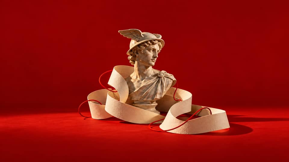 Marble messenger bust encircled by cream paper and red cord against a red backdrop.